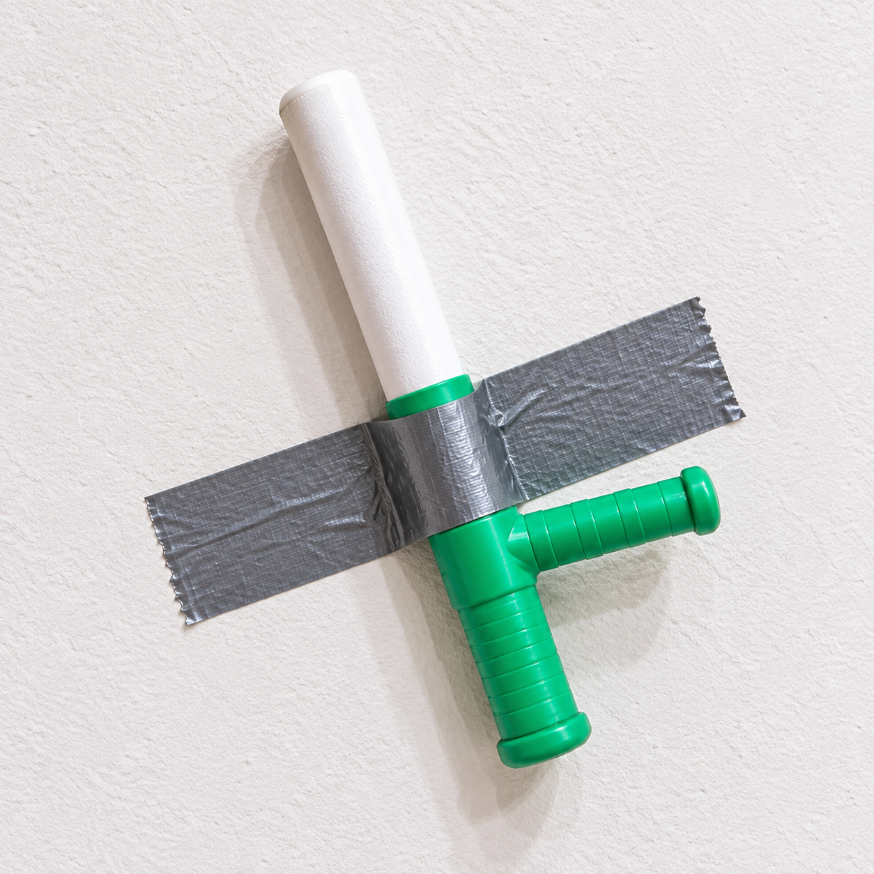 Green and white baton taped to a white wall